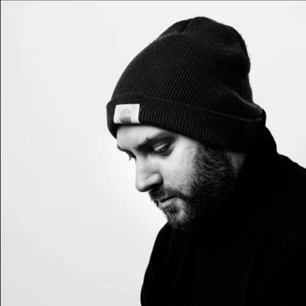 Black and white portrait of Micka in a knit beanie, looking down